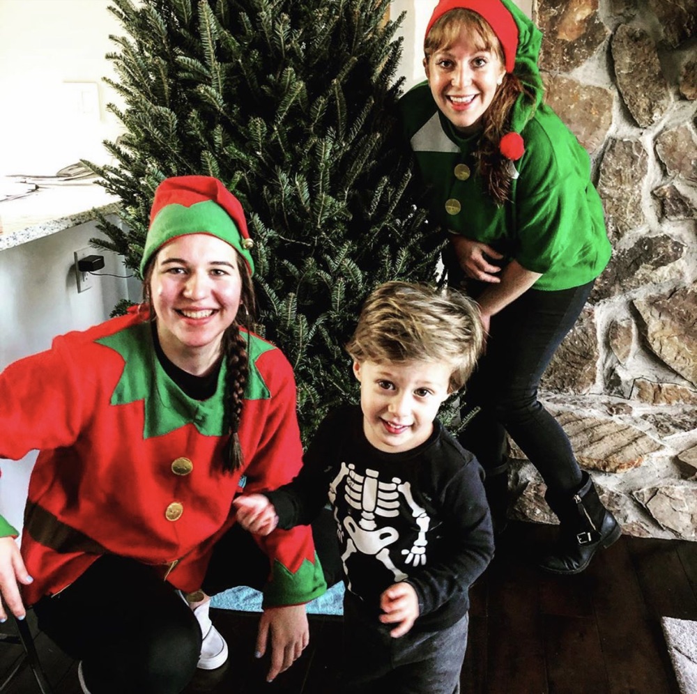 Two elves and a little boy in front of a Fraser fir