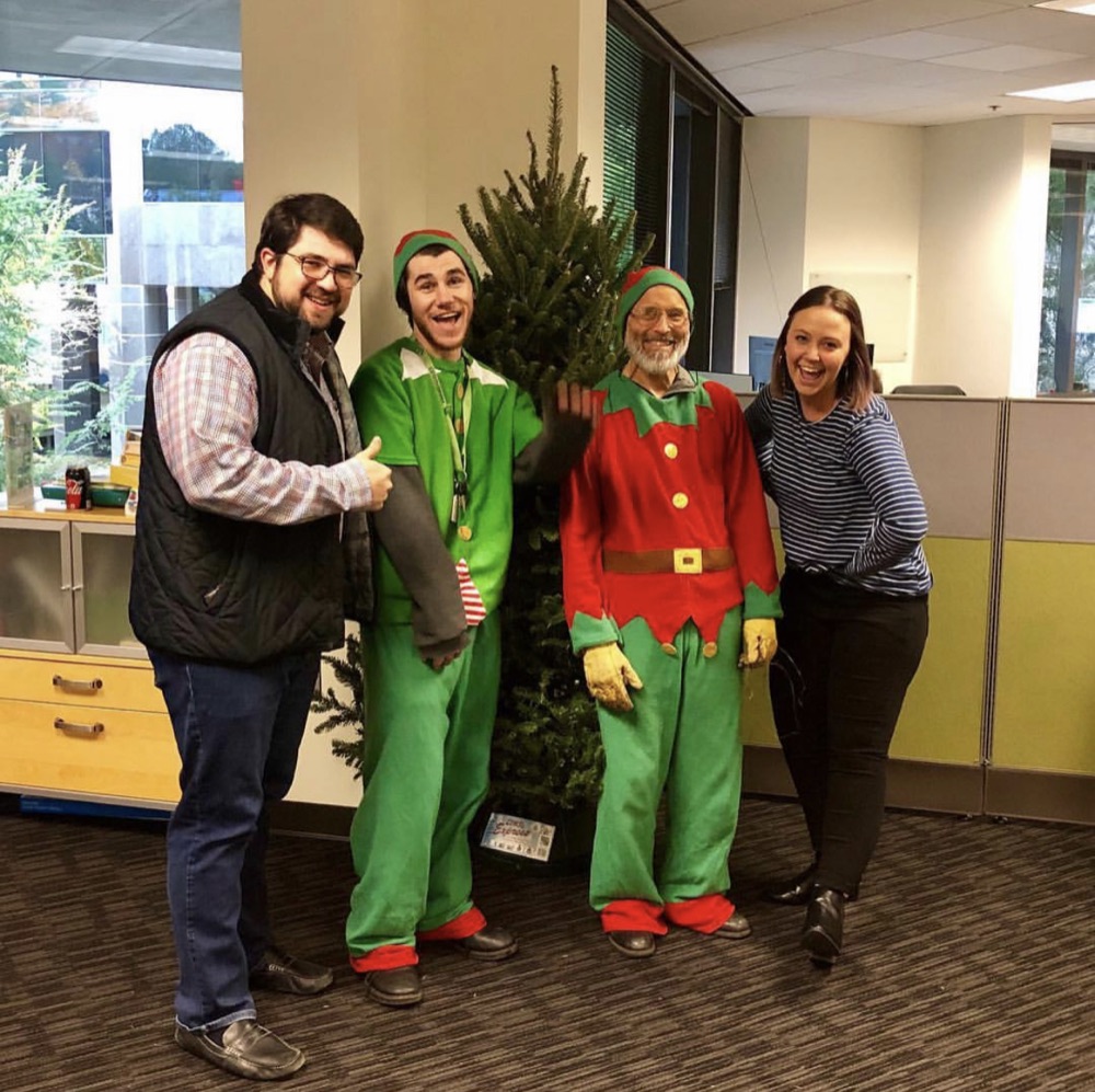 Two elves and an office team around a Fraser fir
