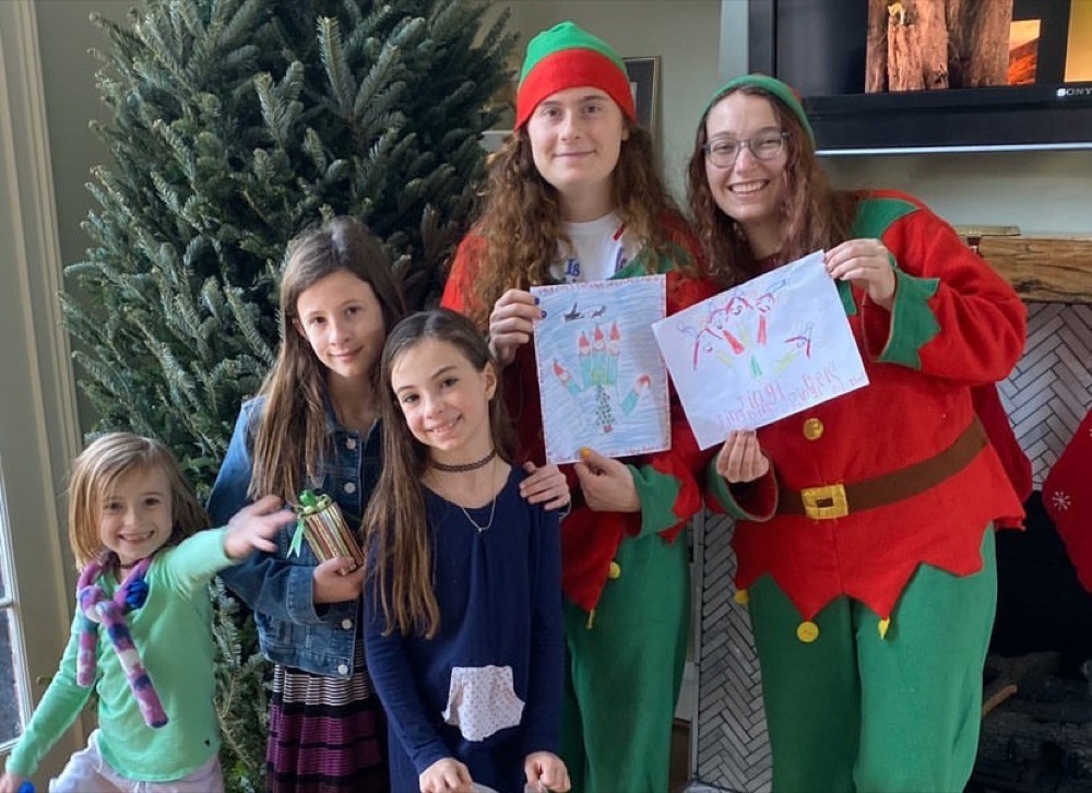 The elves and four kids holding drawings in front of a Fraser fir