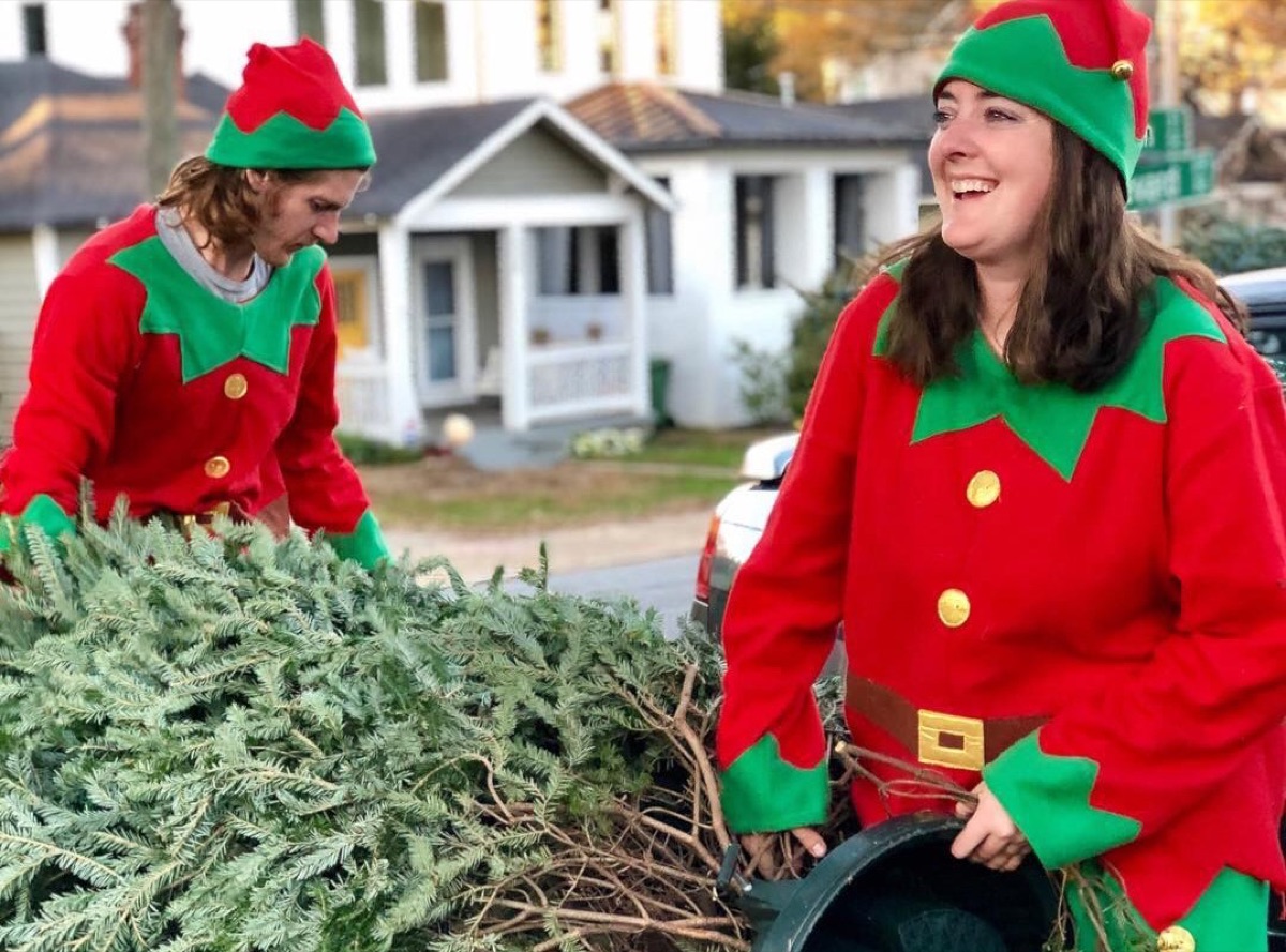 Two elves unloading a fresh-cut Fraser fir on a neighborhood street
